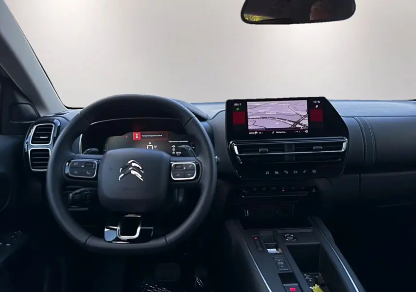 Vue frontale de l’intérieur du Citroën C5 Aircross 2025, volant cuir noir et écran tactile GPS au centre du tableau de bord.