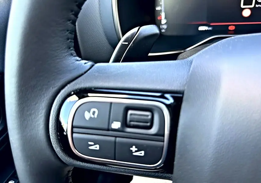 Gros plan sur les commandes gauche du volant cuir noir du Citroën C5 Aircross 2025, avec touches multifonctions.