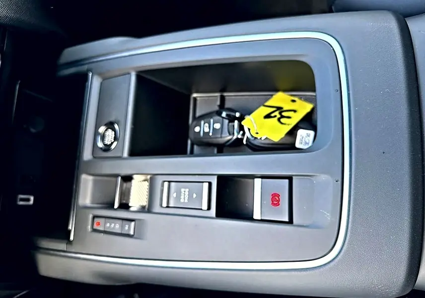 Vue rapprochée de la console centrale grise avec bouton de frein à main électrique et clé de voiture Citroën C5 Aircross blanche.