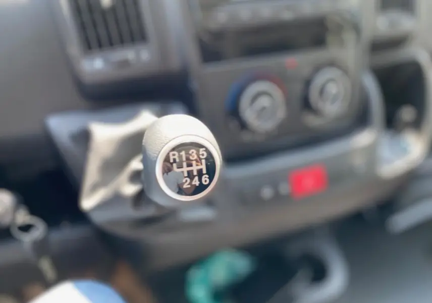 Le levier de vitesses manuel du Citroën Jumper 2023 en gros plan, avec tableau de bord flou en arrière-plan.