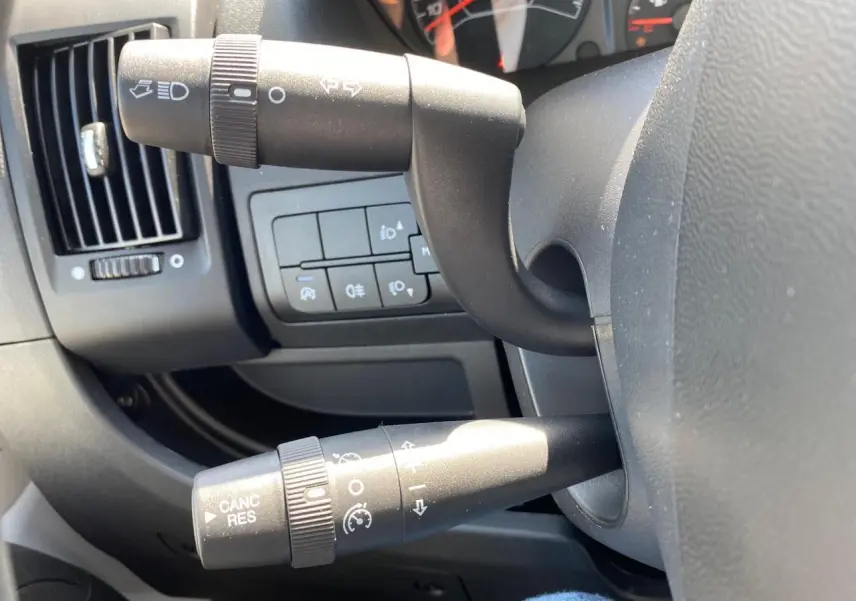 Gros plan sur les commandes de clignotants et régulateur de vitesse du tableau de bord noir du Citroën Jumper 2023.