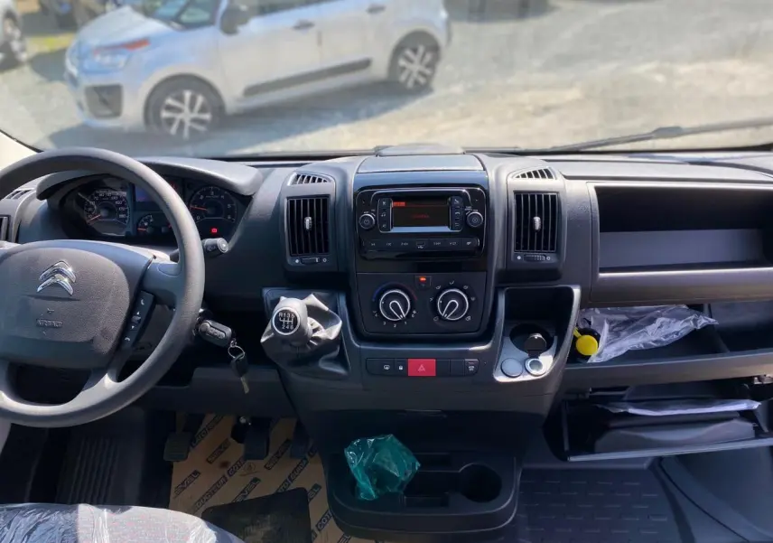 Vue intérieure du tableau de bord du Citroën Jumper blanc 2023 avec volant, boîte manuelle et commandes centrales visibles.