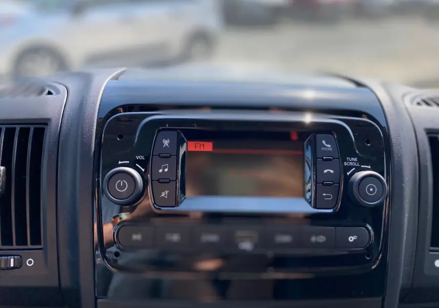 Vue rapprochée de la console centrale noire avec radio FM du Citroën Jumper 2023, intérieur moderne.