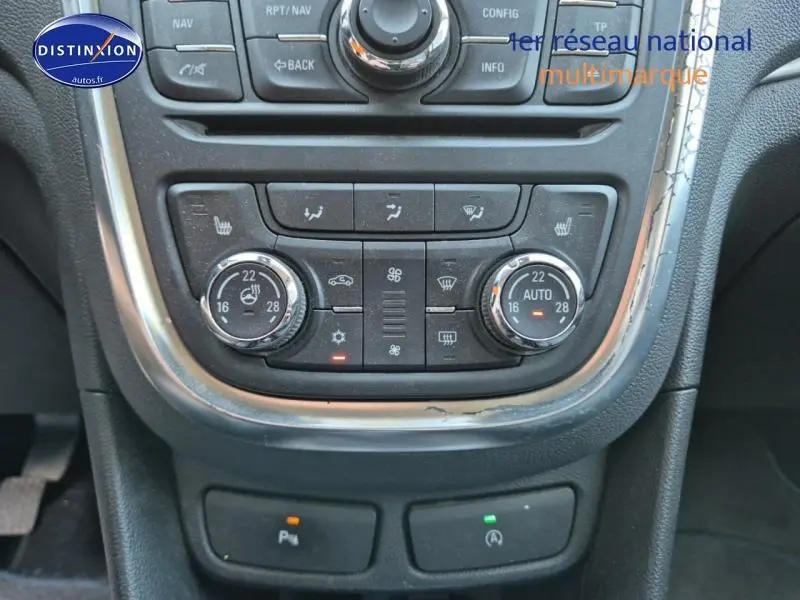 Vue rapprochée du tableau de bord central de l'Opel Mokka gris, montrant les commandes de climatisation automatique bi-zone et sièges chauffants.