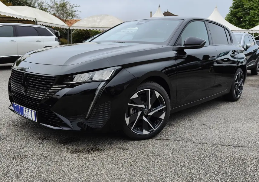 Peugeot 308 PureTech 130 Allure Pack noire vue en 3/4 avant droit avec jantes bi-ton et calandre noire brillante.