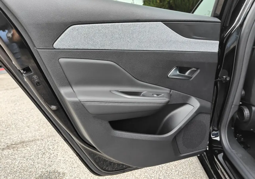 Vue rapprochée de la porte arrière gauche noire de la Peugeot 308 PureTech 130 Allure Pack 2023, avec garniture grise et commandes de fenêtre.