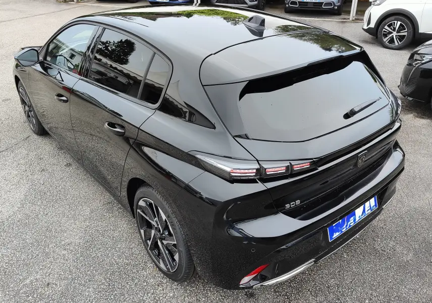 Vue 3/4 arrière droite d'une Peugeot 308 noire 2023 avec feux arrière LED et jantes alliage biton.
