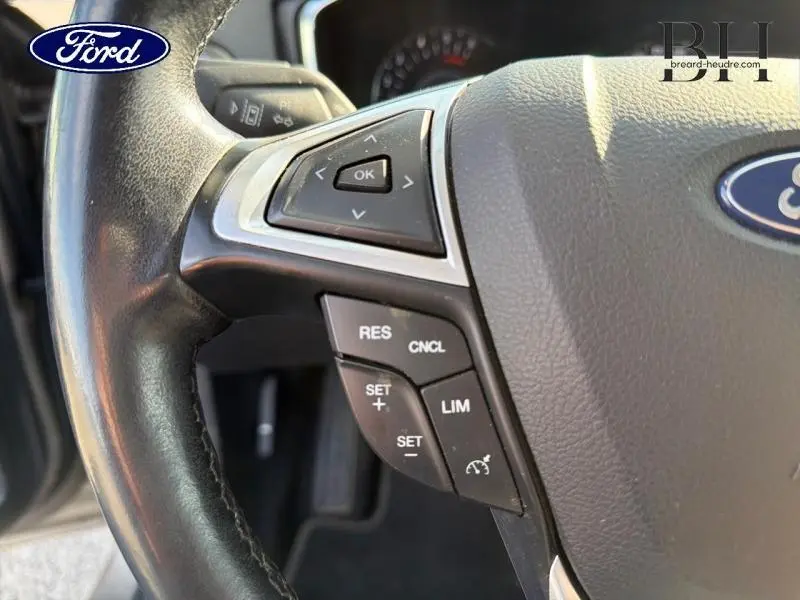 Gros plan sur le volant cuir noir de la Ford Mondeo 2021 avec commandes multifonctions et bouton OK visible.