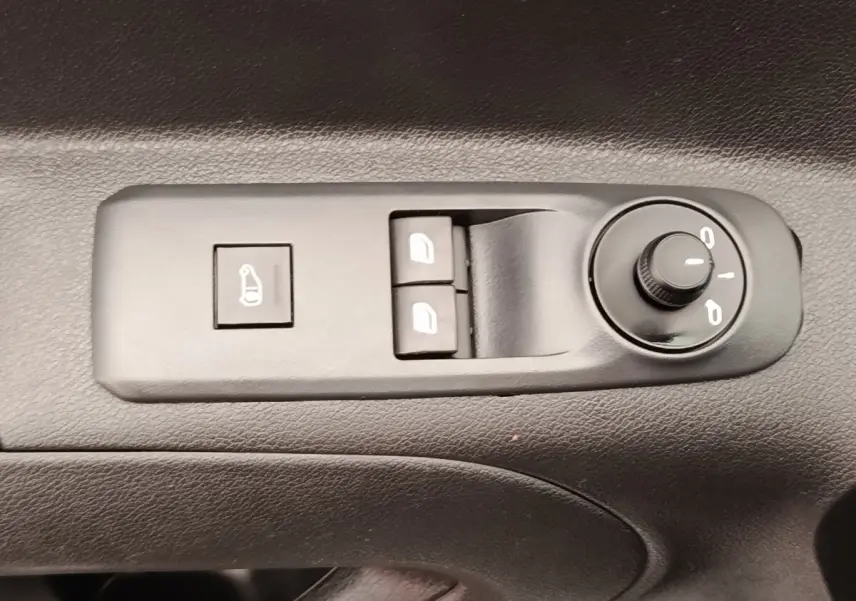 Gros plan sur les commandes de réglage des rétroviseurs et des vitres électriques côté conducteur du Peugeot Partner blanc.