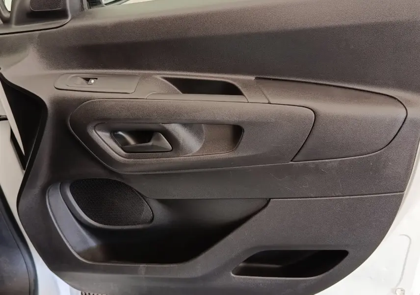 Vue rapprochée de la porte avant gauche noire du Peugeot Partner blanc, avec poignée intérieure et haut-parleur intégré.