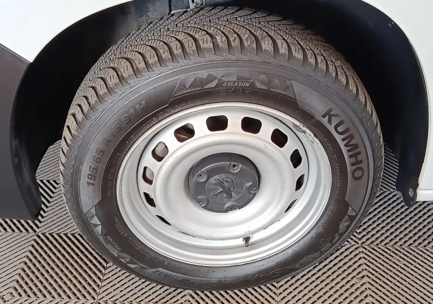Gros plan sur la roue avant droite en jante acier du Peugeot Partner blanc, montrant le pneu Kumho 4 saisons.
