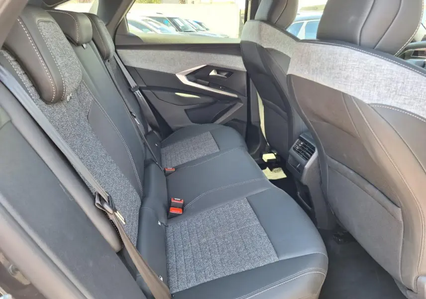 Vue intérieure arrière côté droit du Peugeot 3008 Hybrid 136 Allure 2025, sièges bicolores gris et noir avec surpiqûres.
