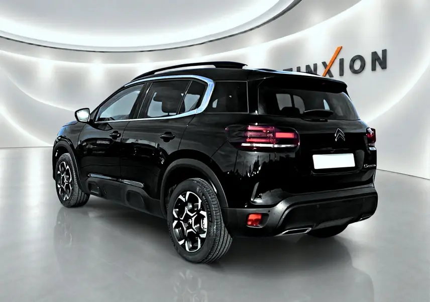 Vue 3/4 arrière droite du Citroën C5 Aircross noir 2025 avec jantes alu et barres de toit visibles.