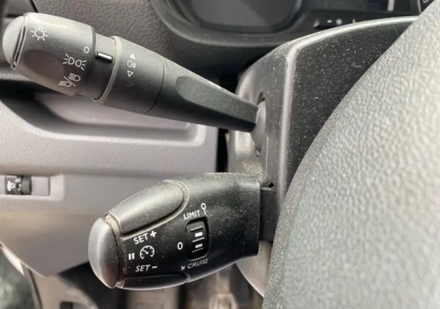 Gros plan sur les commandes de régulateur de vitesse et éclairage du tableau de bord d'un Citroën Jumpy blanc de 2019.