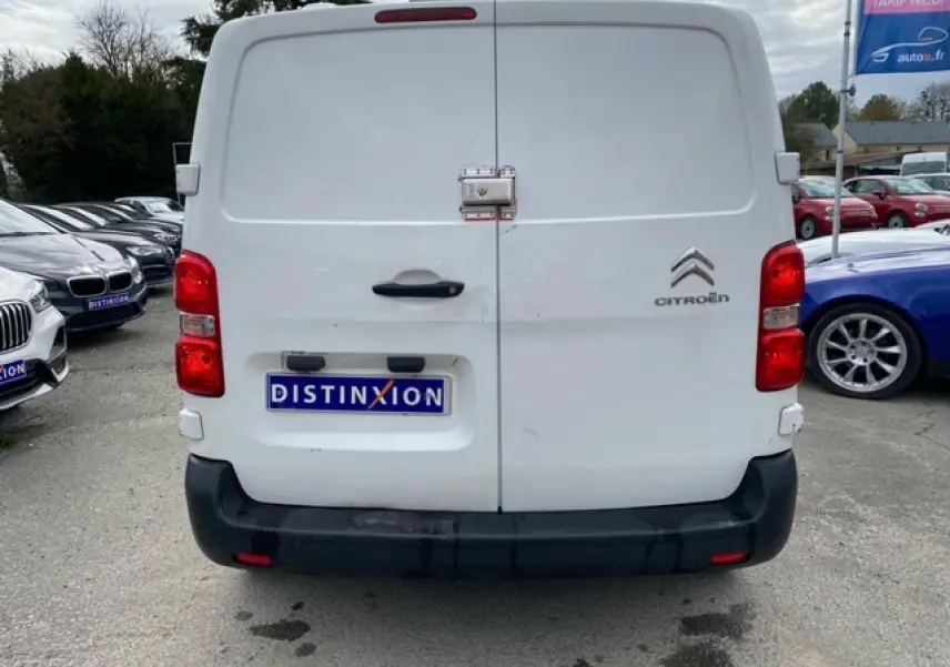 Vue arrière d'un utilitaire blanc Citroën Jumpy 2019 avec portes battantes et logo visible sur parking.