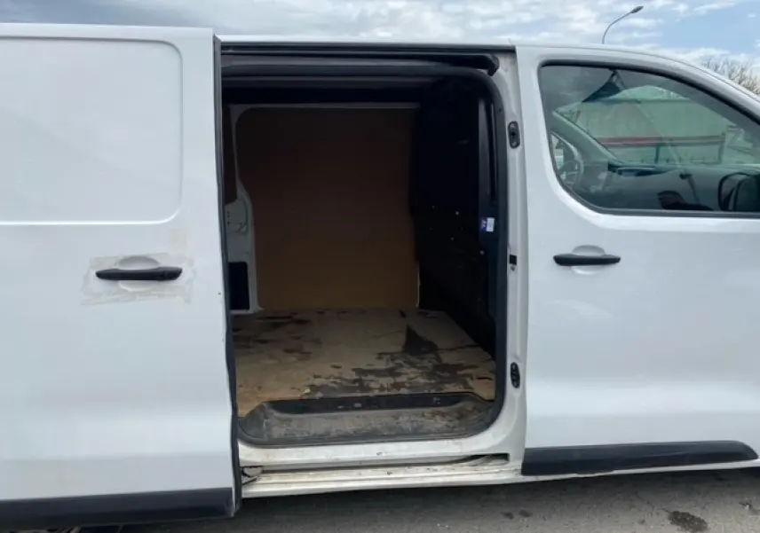 Vue latérale droite d'un utilitaire Citroën Jumpy blanc avec porte coulissante ouverte montrant l'espace de chargement en bois.