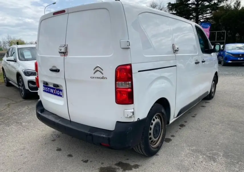 Vue 3/4 arrière droite d'un utilitaire Citroën Jumpy blanc avec portes arrière battantes et porte latérale coulissante.