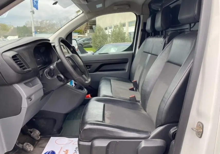 Vue intérieure côté conducteur du Citroën Jumpy blanc 2019, sièges mixtes TEP/tissu et tableau de bord simple.