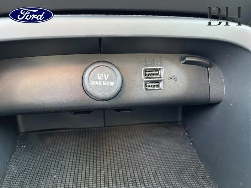 Prise 12V et double port USB visibles en gros plan dans la console centrale d'un Volvo XC40 gris Glacier.