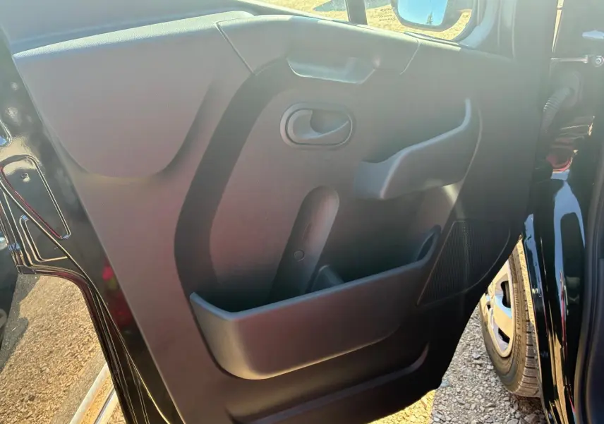 Vue rapprochée de la porte intérieure côté gauche du Renault Master gris 2023, montrant la poignée et les rangements.