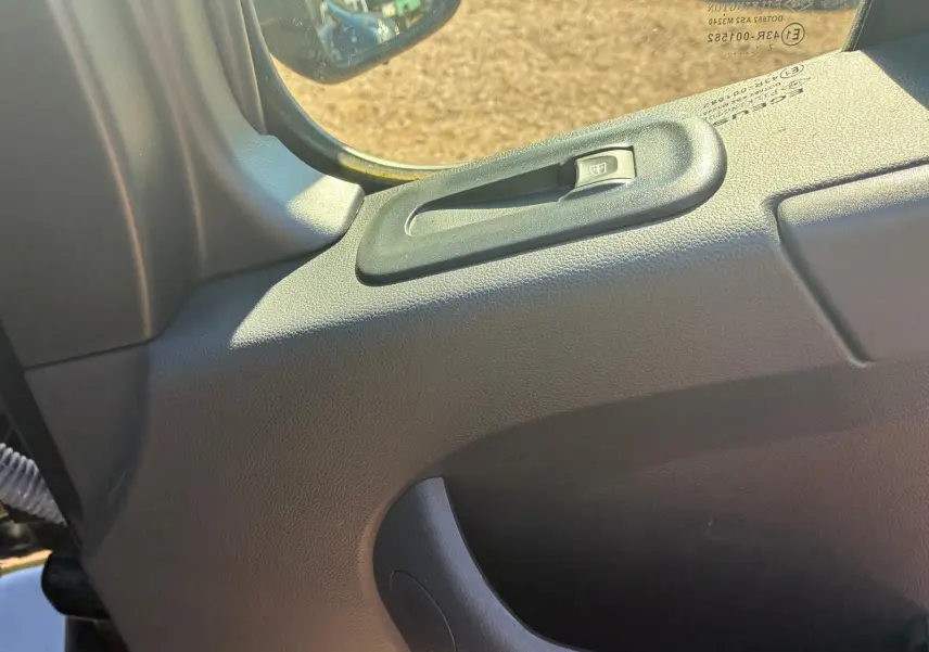 Détail de la commande de lève-vitre côté gauche dans l’habitacle du Renault Master gris 2023.