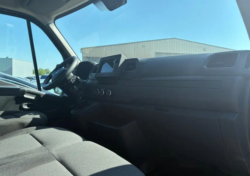 Vue intérieure côté conducteur du tableau de bord et des sièges en tissu gris du Renault Master 2023.