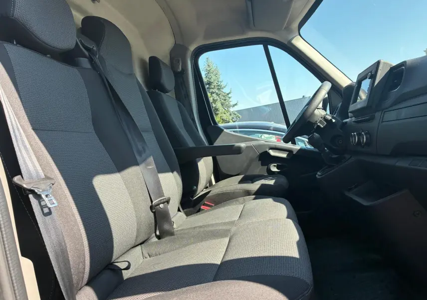 Vue intérieure côté conducteur du Renault Master gris 2023, montrant les sièges tissu gris et le tableau de bord avec écran tactile.