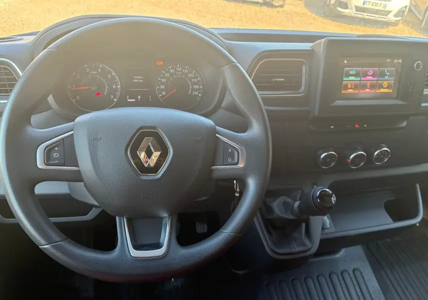 Vue intérieure centrée sur le volant Renault et le tableau de bord avec écran tactile et levier de vitesses manuel.