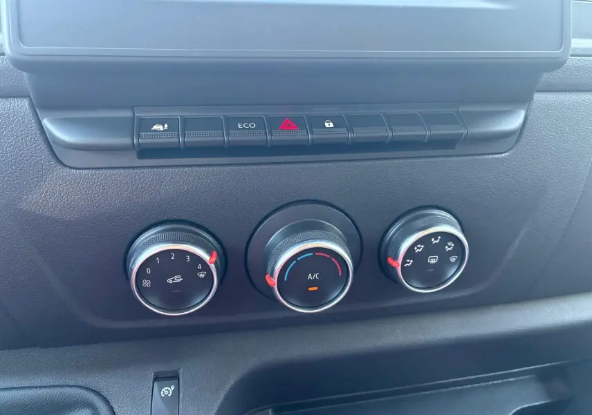 Gros plan sur les commandes de climatisation et les boutons de fonction du tableau de bord noir du Renault Master gris 2023.