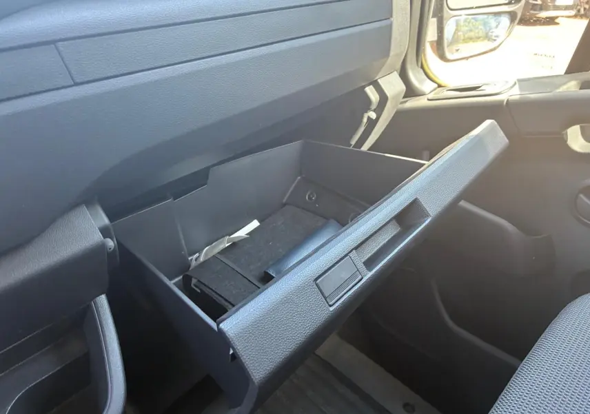 Vue intérieure côté passager du Renault Master 2023, boîte à gants ouverte avec rangement noir visible.