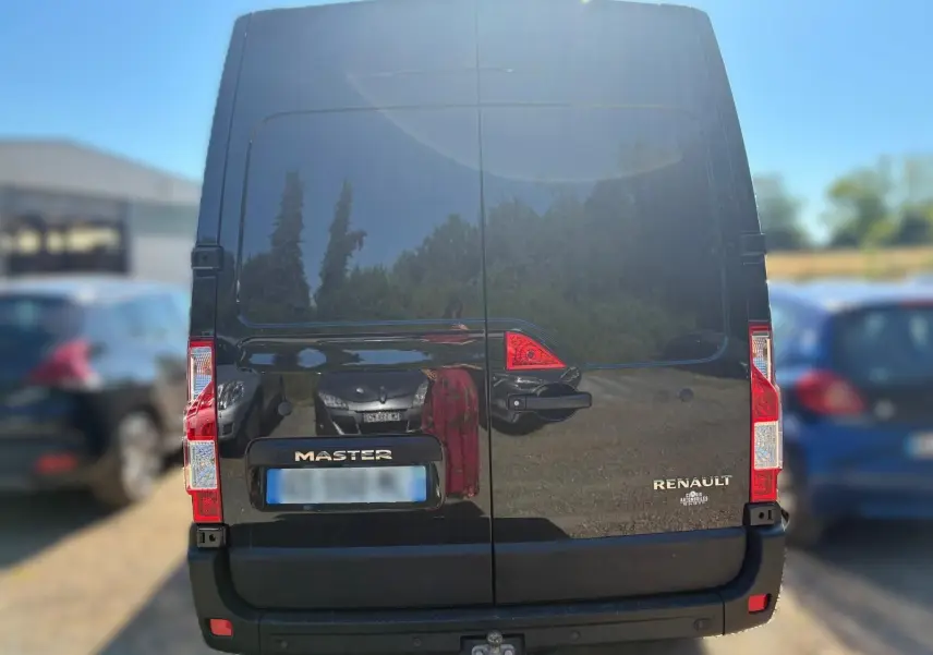 Vue arrière d’un Renault Master gris 2023 avec portes battantes et attelage visible en bas.