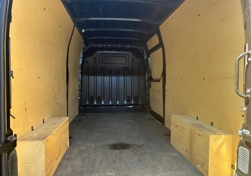 Vue intérieure arrière du Renault Master gris 2023, montrant l'espace de chargement avec parois et coffres en bois clair.