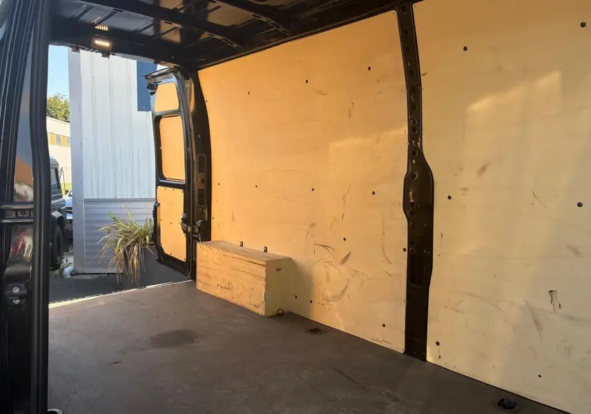 Vue intérieure arrière du Renault Master gris 2023, montrant l'espace de chargement avec parois en bois et porte ouverte côté gauche.