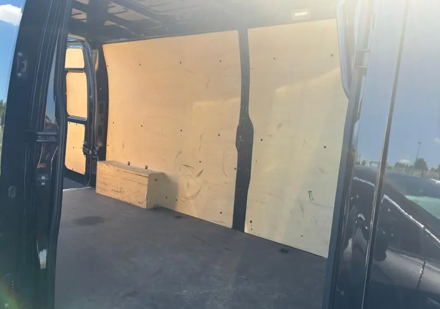 Vue intérieure côté droit du coffre d’un Renault Master gris 2023 avec parois en bois et plancher noir.