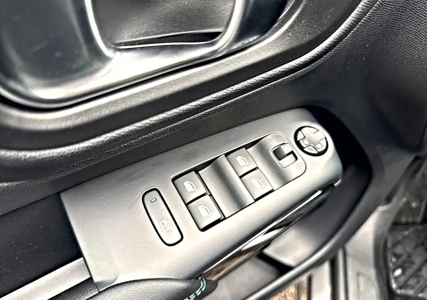Gros plan sur les commandes des vitres électriques et rétroviseurs sur la porte côté conducteur d’un Citroën C5 Aircross gris.