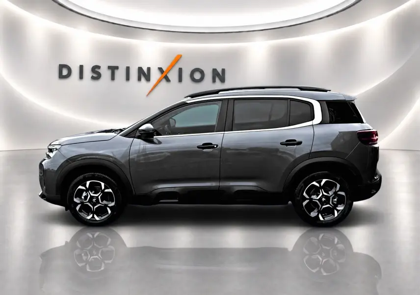 Vue de profil droit du Citroën C5 Aircross gris platinium 2025 avec barres de toit et jantes alu distinctives.