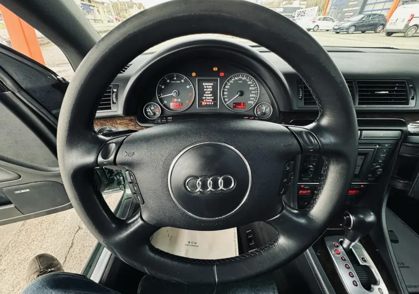 Vue intérieure centrée sur le volant cuir noir et le tableau de bord de l'Audi S4 Avant vert de 2004.