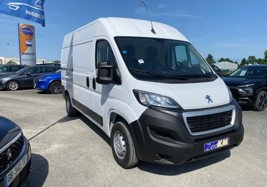Vue 3/4 avant d'un Peugeot Boxer Fourgon blanc 2023 avec pare-chocs noirs et porte latérale droite coulissante.