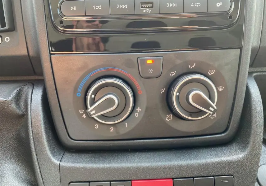Gros plan sur les commandes de climatisation manuelle et audio du Peugeot Boxer Fourgon blanc 2023.
