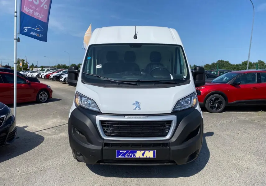 Vue frontale d'un Peugeot Boxer Fourgon blanc 2023 avec pare-chocs noir et plaque "Zéro KM" visible.