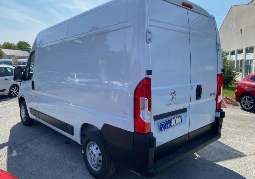 Vue 3/4 arrière droite d'un Peugeot Boxer Fourgon blanc 2023 avec portes arrière tôlées et porte latérale coulissante.