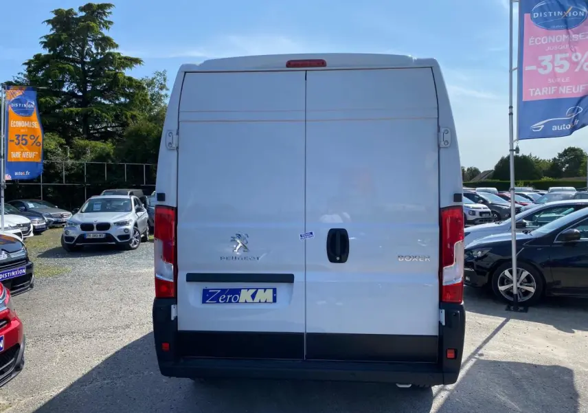 Vue arrière d'un Peugeot Boxer Fourgon blanc 2023 avec portes battantes et logo visible sur un parking.