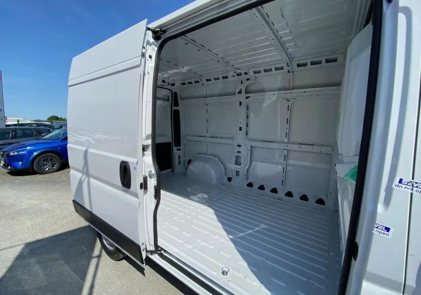 Vue latérale gauche du Peugeot Boxer Fourgon blanc 2023 avec porte coulissante ouverte montrant l'intérieur vide et tôlé.