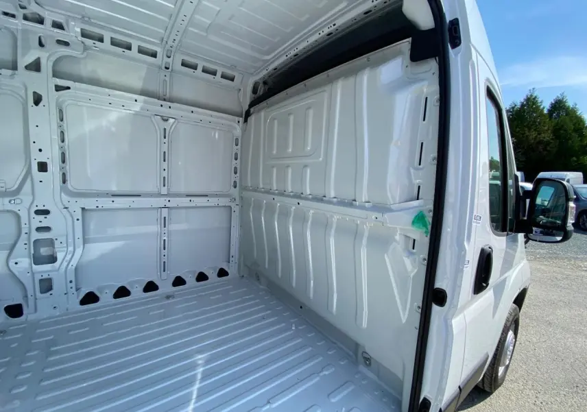 Vue intérieure de la zone de chargement blanche du Peugeot Boxer Fourgon L2H2 avec porte latérale droite ouverte.