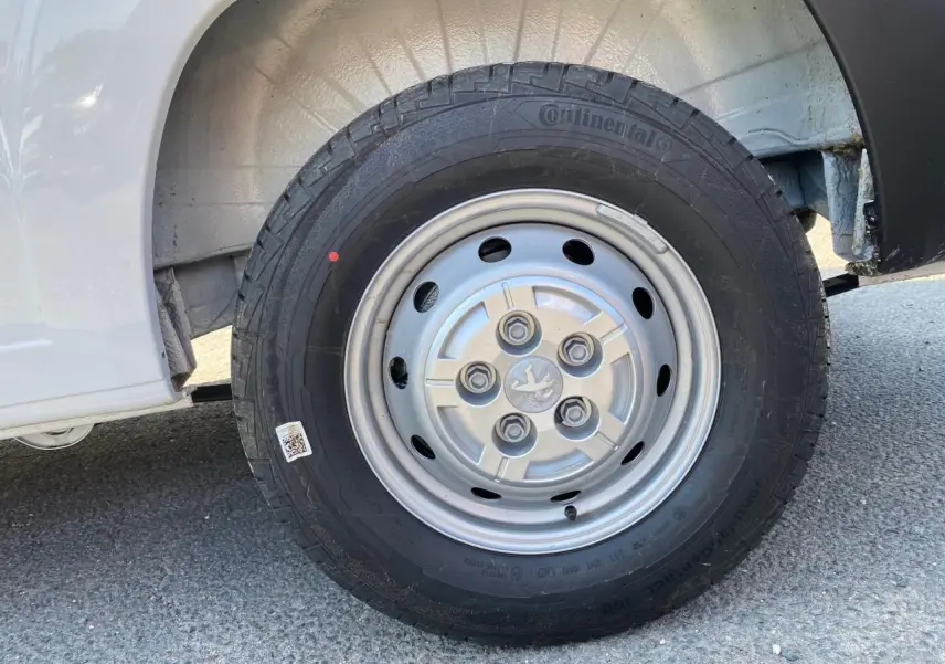 Gros plan sur la roue avant gauche blanche d'un Peugeot Boxer Fourgon 2023 avec jante acier et pneu Continental.