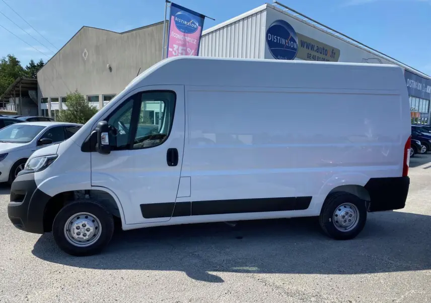 Vue latérale gauche d'un Peugeot Boxer Fourgon blanc 2023 avec porte latérale coulissante et protections noires.