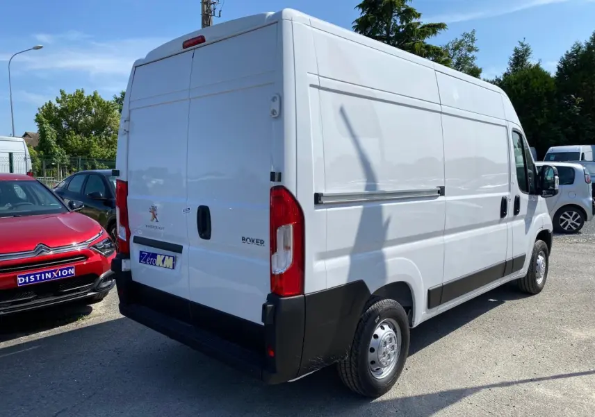 Vue 3/4 arrière droite d'un utilitaire Peugeot Boxer Fourgon blanc avec portes arrière battantes et porte latérale tôlée.