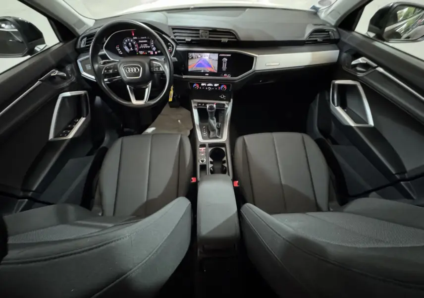 Vue intérieure avant de l'Audi Q3 noir 2022, tableau de bord digital et écran central avec caméra de recul affichée.