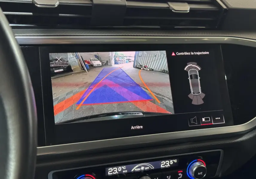 Écran tactile intérieur d’Audi Q3 noir 2022 montrant la caméra de recul avec guidage de trajectoire et capteurs arrière.