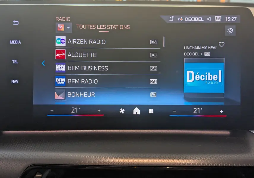 Écran tactile central du BMW X1 noir 2025 affichant les stations radio avec interface moderne et réglage de température à 21°C.